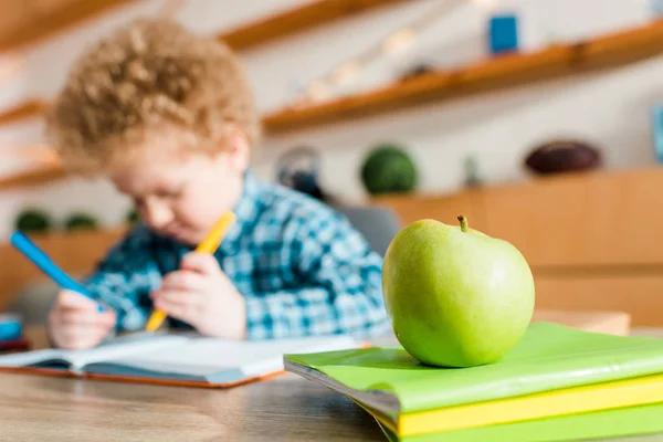 Selective focus of ripe green apple near smart kid — Stock Photo