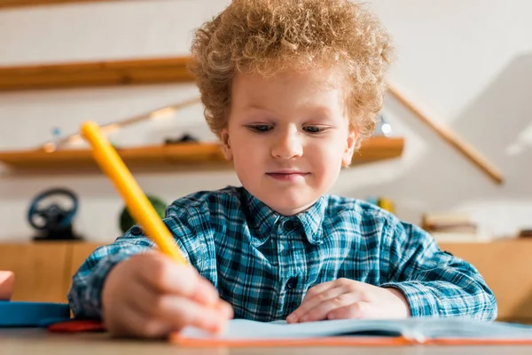 Enfoque selectivo de la escritura inteligente niño en el cuaderno - foto de stock