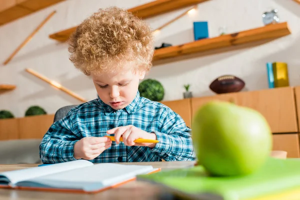 Fuoco selettivo del bambino carino e intelligente che tiene la penna vicino alla mela verde — Foto stock