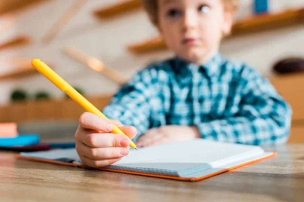Mise au point sélective du stylo à la main sur mignon et intelligent enfant — Photo de stock