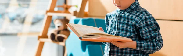 Panoramic shot of cute little boy reading book — Stock Photo