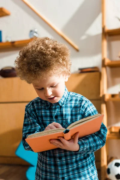 Niño inteligente sonriendo mientras lee libro — Stock Photo