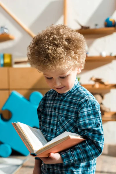 Sorridente e inteligente livro de leitura infantil em casa — Fotografia de Stock