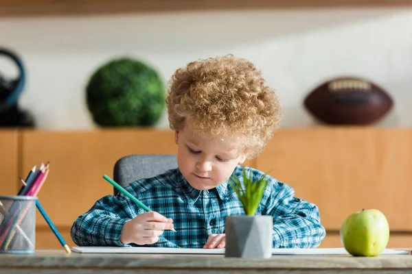 Foco seletivo de criança inteligente e encaracolado desenho perto de maçã madura na mesa — Fotografia de Stock