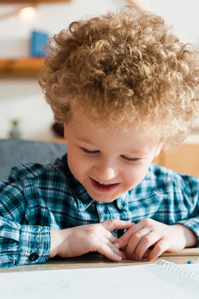 Enfant joyeux souriant tout en regardant du papier vierge sur une table en bois — Photo de stock