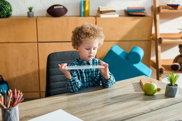 Smart and curly kid looking at digital tablet at home — Stock Photo
