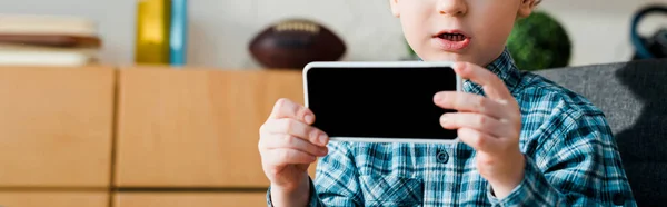 Plano panorámico de niño lindo sosteniendo teléfono inteligente con pantalla en blanco - foto de stock