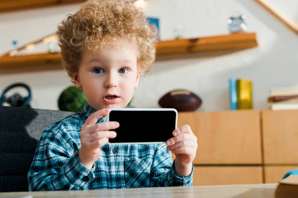 Inteligente niño sosteniendo teléfono inteligente con pantalla en blanco - foto de stock