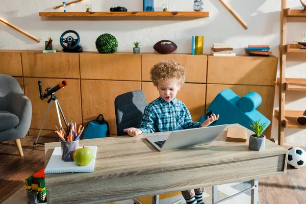 Розумна дитина використовує ноутбук біля свіжого яблука на столі — стокове фото