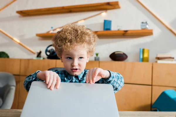 Adorável e inteligente criança tocando laptop enquanto estuda em casa — Fotografia de Stock