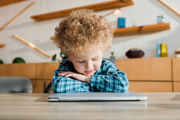 Застенчивый малыш смотрит на ноутбук дома — стоковое фото