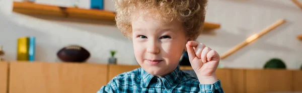 Tiro panorámico de niño feliz y rizado gesto mientras mira a la cámara - foto de stock