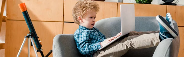 Панорамный снимок умного и вьющегося ребенка с помощью ноутбука — стоковое фото