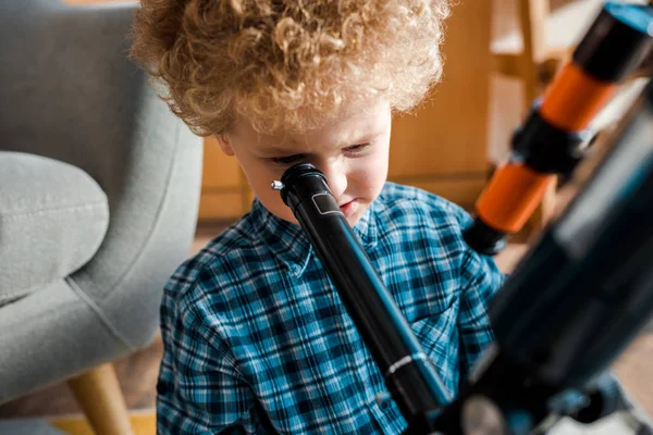 Selective focus of cute and smart child looking through telescope — Stock Photo