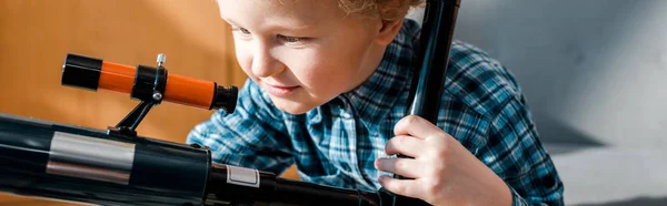 Panoramic shot of smart child looking at telescope — Stock Photo