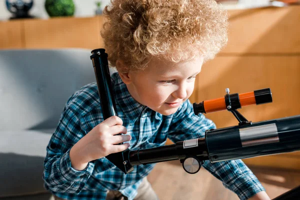 Enfant intelligent souriant tout en regardant le télescope — Photo de stock