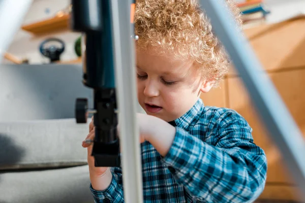 Селективный фокус кудрявого ребенка, смотрящего на телескоп — стоковое фото