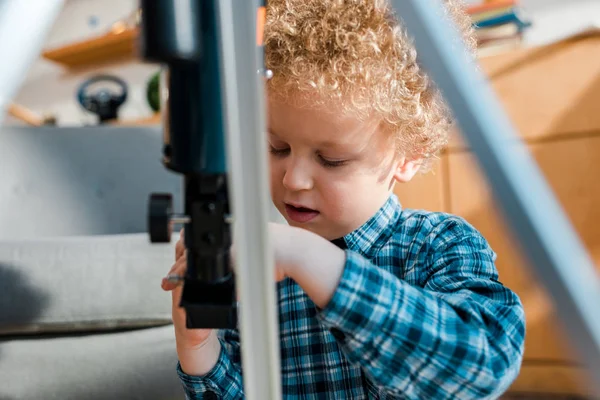 Foyer sélectif du gamin bouclé regardant le télescope — Photo de stock