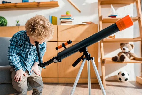 Criança inteligente em camisa xadrez olhando através do telescópio — Fotografia de Stock