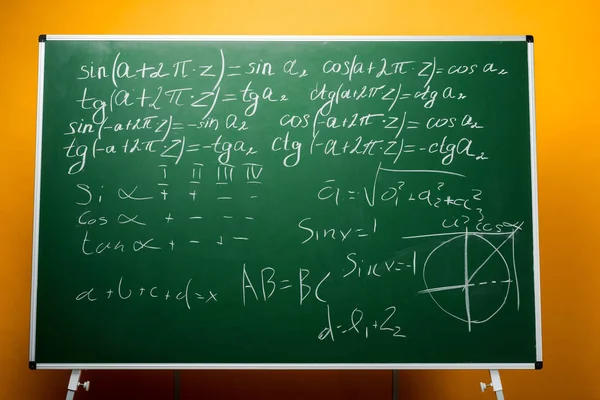 Pizarra verde con fórmulas matemáticas sobre naranja - foto de stock