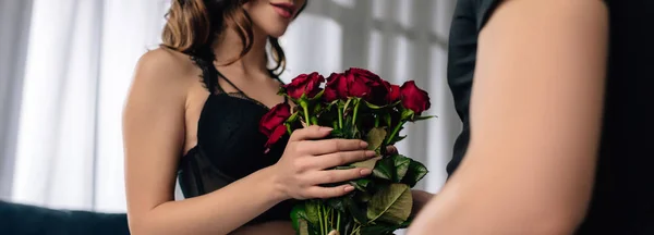 Panoramic shot of girlfriend in black bra holding bouquet of roses in 14 february — Stock Photo