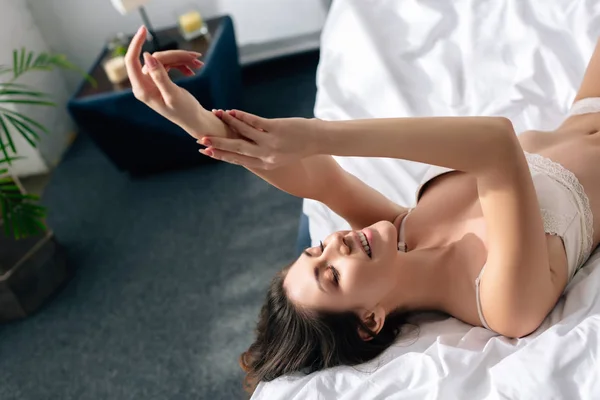 Улыбающаяся и привлекательная женщина в кружевном лифчике лежит на кровати — стоковое фото