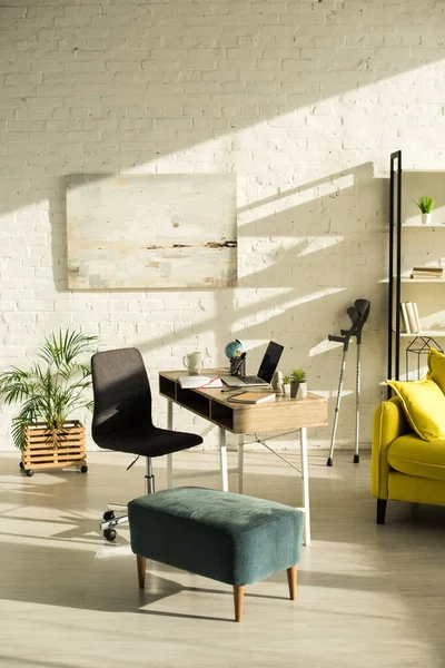 Living room with laptop on table and crutches near wall — Stock Photo