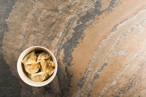 Vista superior de delicioso varenyky com cebola frita na tigela na superfície de pedra — Fotografia de Stock