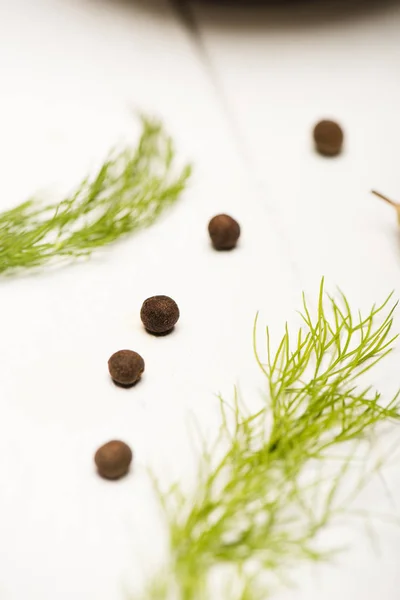 Close up view of dill and black peppercorns on white wooden table — Stock Photo