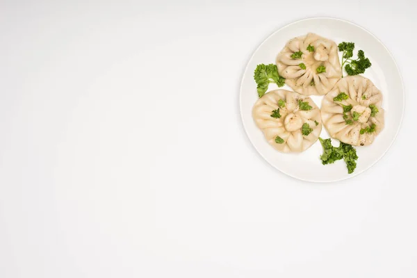 Vista superior de la deliciosa Khinkali con cilantro en plato sobre fondo blanco - foto de stock