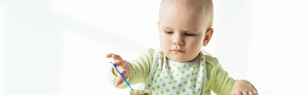 Панорамний знімок немовляти, що тримає ложку в банці рослинного дитячого харчування на білому тлі — стокове фото