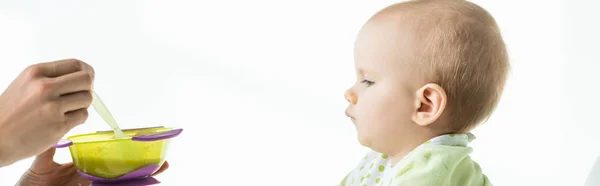 Vue latérale de la mère avec bol de nutrition pour bébé près du fils isolé sur blanc, panoramique — Photo de stock