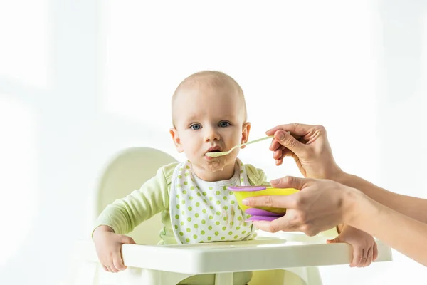 Mãe que alimenta o bebê na cadeira de alimentação com nutrição do bebê no fundo branco — Fotografia de Stock