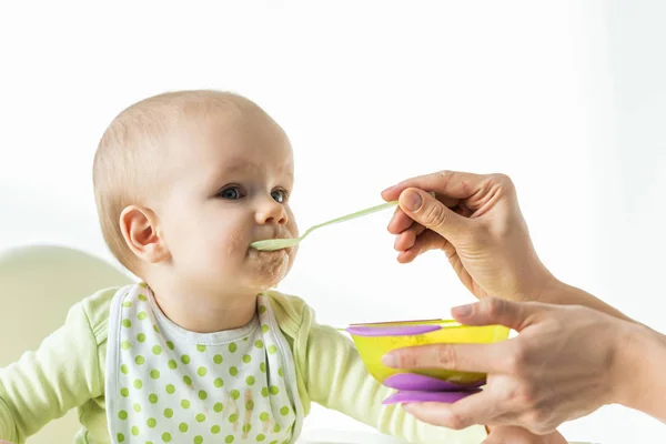 Мать кормит ребенка с детским питанием на белом фоне — стоковое фото