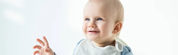 Plan panoramique de bébé mignon souriant tout en étant assis sur une chaise d'alimentation sur fond blanc — Photo de stock