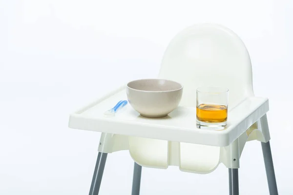 Chaise d'alimentation avec bol, cuillère et verre de jus de pomme sur la table isolé sur blanc — Photo de stock