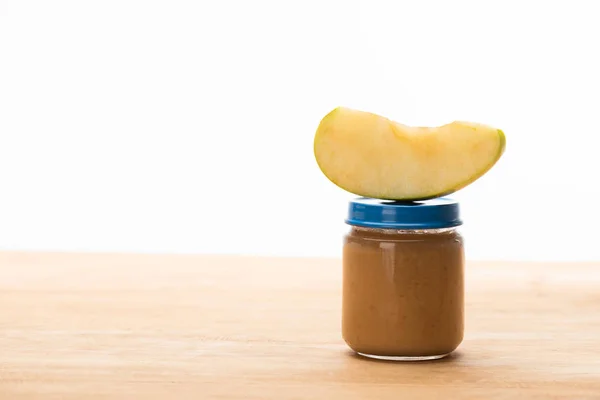 Peça de maçã no frasco com nutrição de bebê de frutas na superfície de madeira isolada no branco — Fotografia de Stock