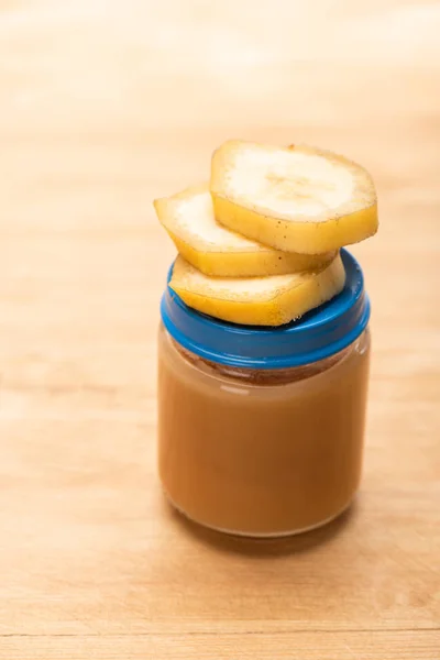 Vista de perto do pote com nutrição de frutas e fatias de banana na superfície de madeira — Fotografia de Stock