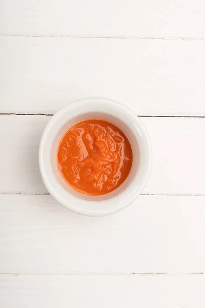 Верхний вид морковного пюре в миске на белом деревянном фоне — стоковое фото