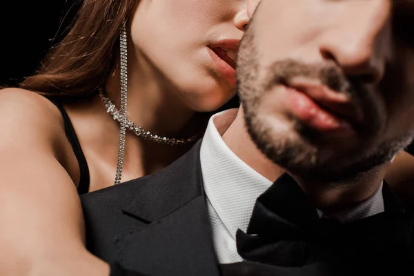 Обрезанный вид девушки, целующейся с бородатым мужчиной, изолирован на черном — стоковое фото