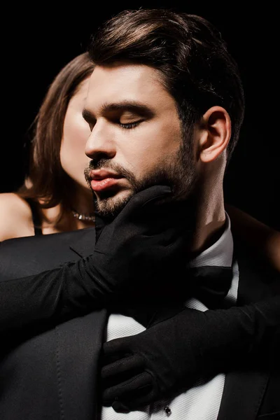 Молодая женщина в перчатках касаясь бородатый мужчина изолирован на черный — стоковое фото