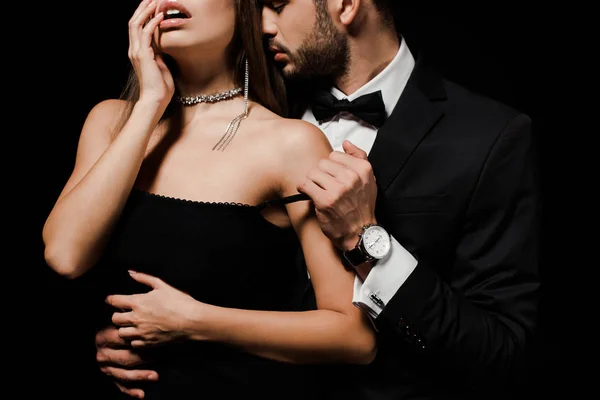 Обрізаний вид пристрасного чоловіка, роздягається сексуальна жінка ізольована на чорному — стокове фото