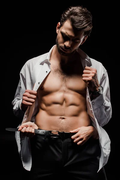 Woman touching belt while undressing muscular man isolated on black — Stock Photo