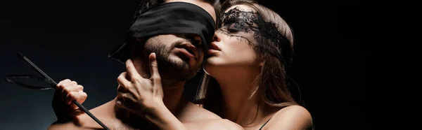 Plan panoramique de la femme dominante tenant fouet fouet près soumis et les yeux bandés homme sur noir — Photo de stock