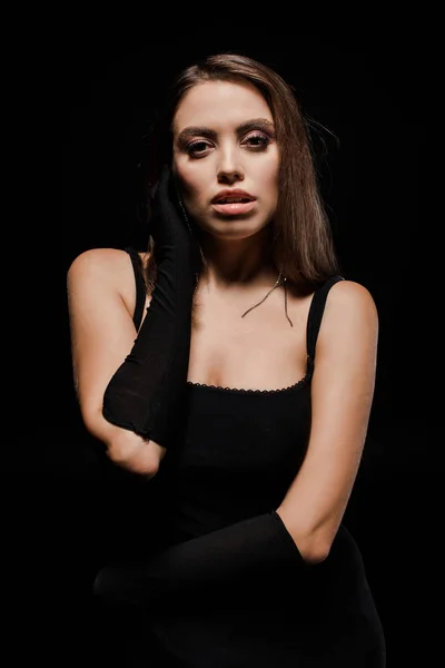 Atractiva mujer en guantes mirando a la cámara aislada en negro — Stock Photo