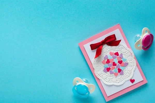 Top view of greening card with pacifiers on blue surface, concept of mothers day — Stock Photo