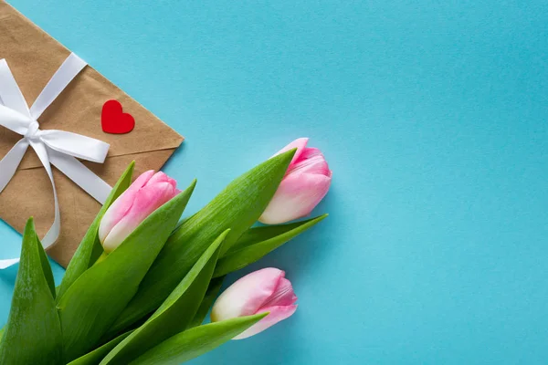 Draufsicht auf Tulpen mit Umschlag auf blauem Hintergrund mit Kopierraum — Stockfoto