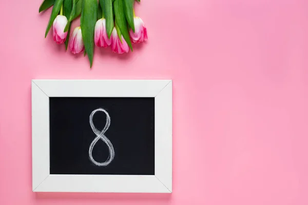 Top view of 8 number on chalkboard near tulips on pink background — Stock Photo