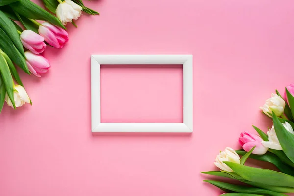 Vista dall'alto di cornice bianca con tulipani su sfondo rosa con spazio di copia — Foto stock