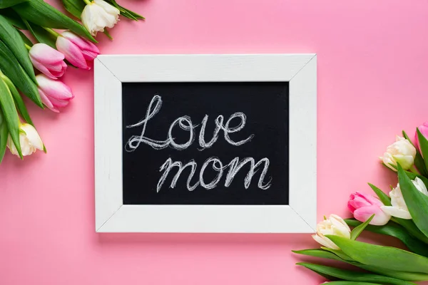 Вид зверху на крейдяну дошку з любов'ю мамині написи та тюльпани на рожевому фоні — стокове фото